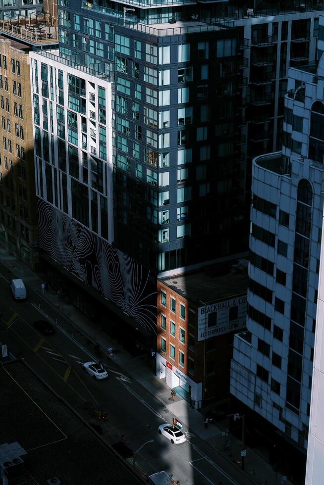 Toronto, Canada - 28 October 2023. Aerial view of city streets with a blend of modern skyscrapers and traditional buildings, highlighted by sun rays amidst shadows photo