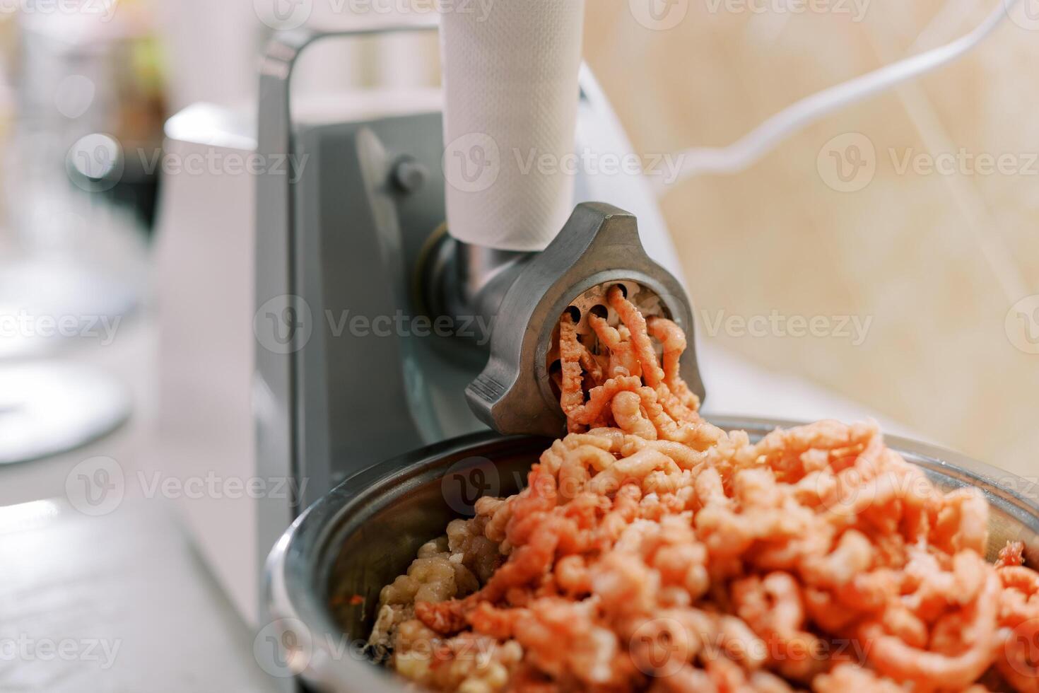 Electric meat grinder twists meat into a pan on the table photo