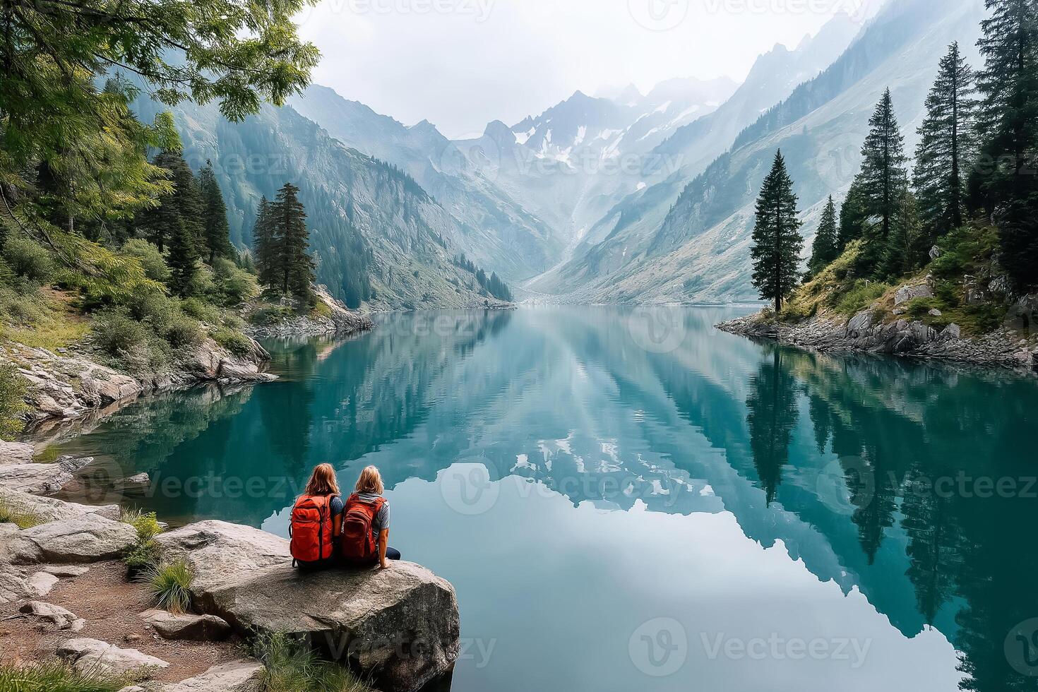 Two people sitting on a rock overlooking a lake photo