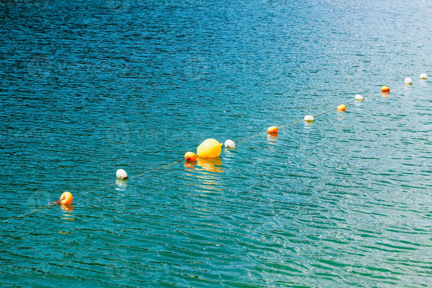 Buoys float on the clear water of a tranquil lake during a bright sunny day photo
