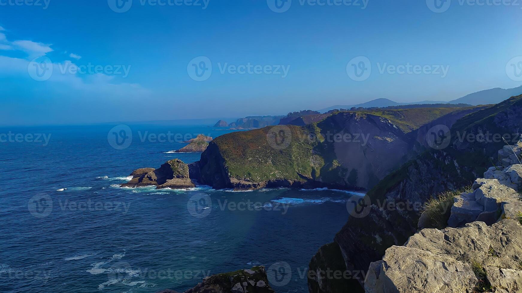 Stunning coastal cliffs overlooking the deep blue sea with distant rock formations and rolling hills. photo