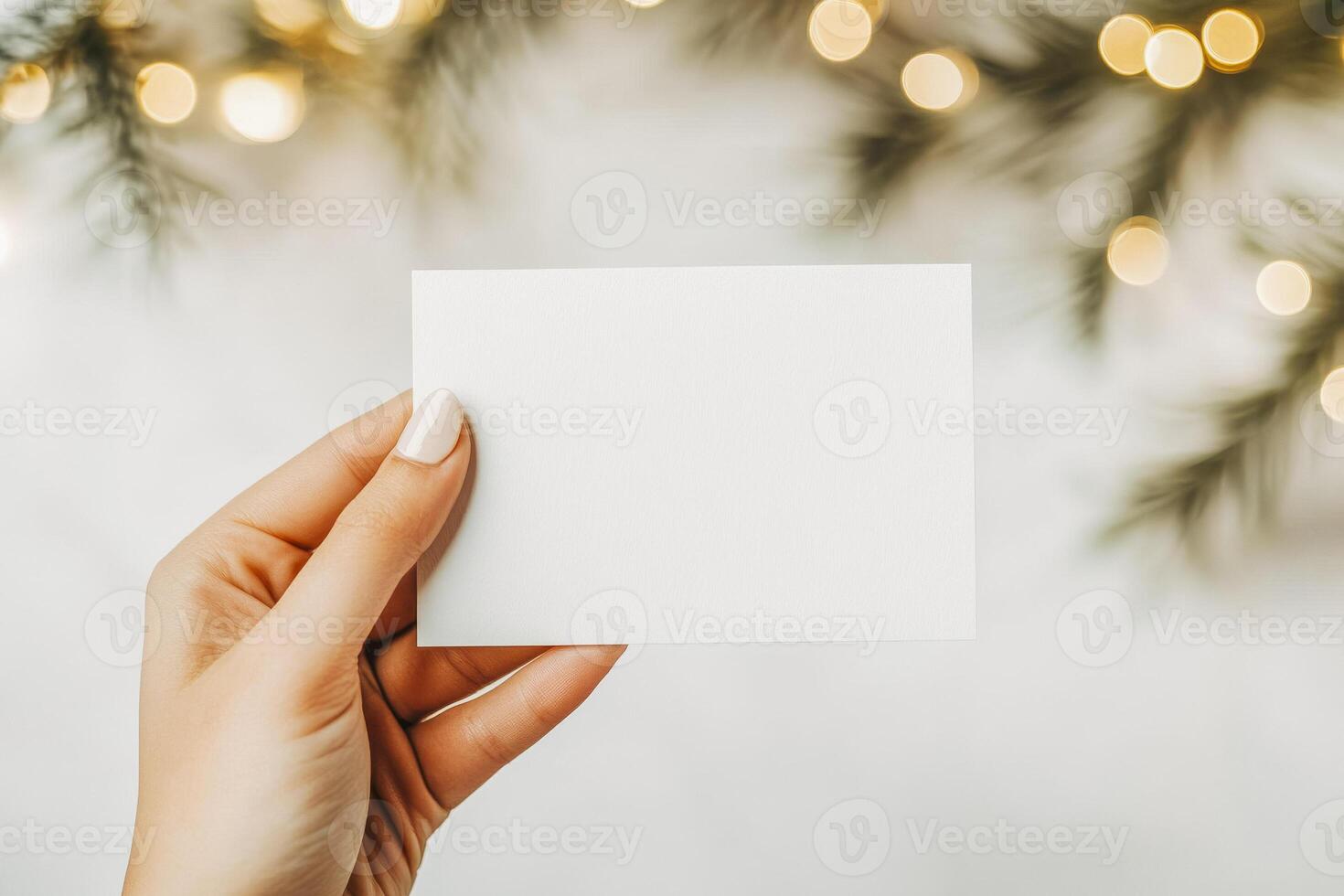 Blank white card with festive lights and evergreen branches for holiday greetings and invitations photo