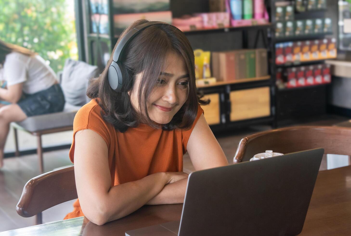 Woman sitting at the cafe using laptop and headphones listen to music, watching social media networks while ,relaxing on vacation lifestyles concepts photo