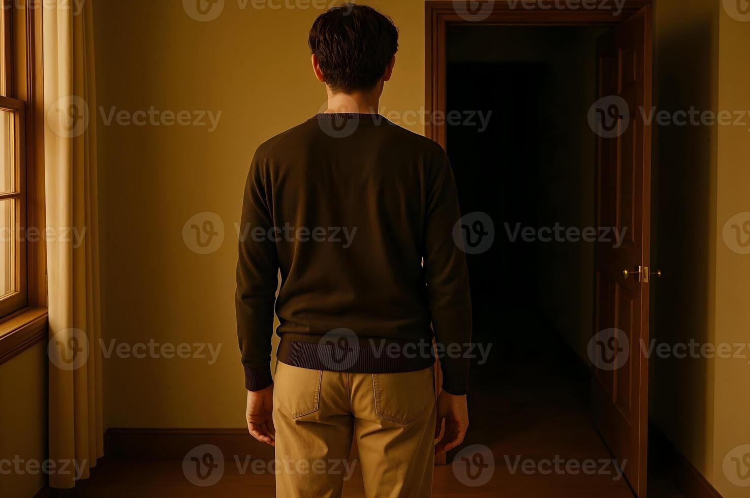 Man facing open doorway in dimly lit hallway photo