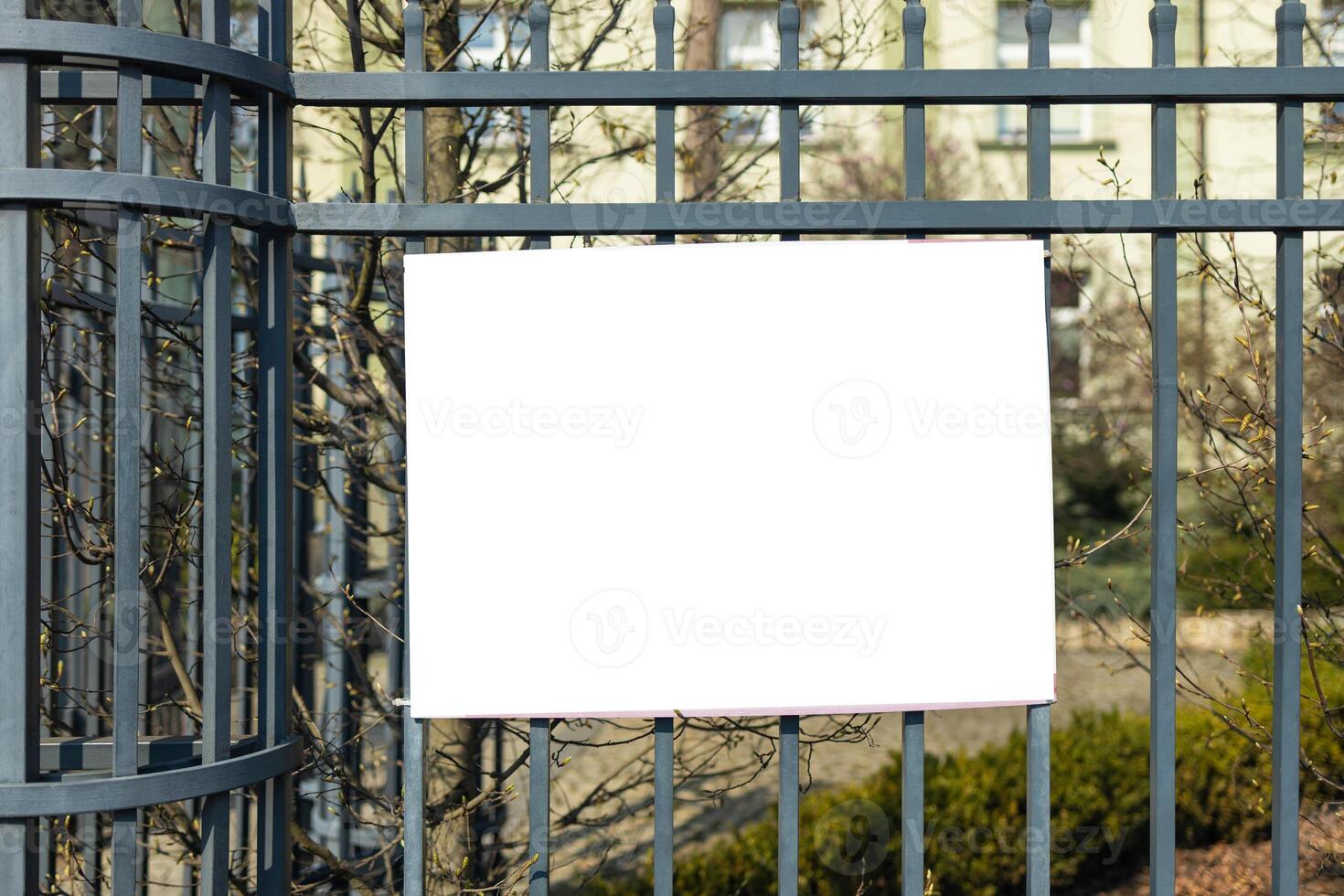 large blank white poster with mockup space hanging on metal fence of play ground outside photo
