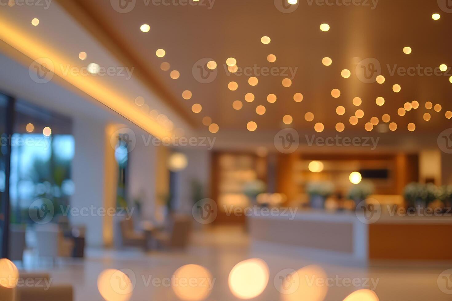 Blurry interior of a hotel lobby with decorative ceiling lights and a counter in the background photo