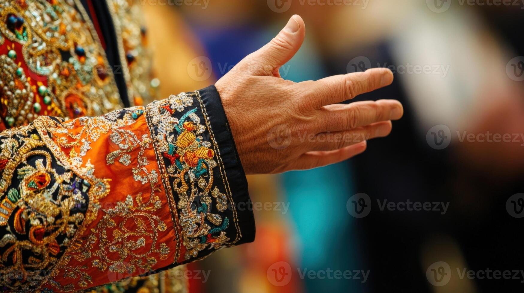 A closeup of a distinguished diplomats hand gesturing expressively while speaking with intricate embroidery on the sleeve of a traditional attire in the foreground emphasizing the cultura photo