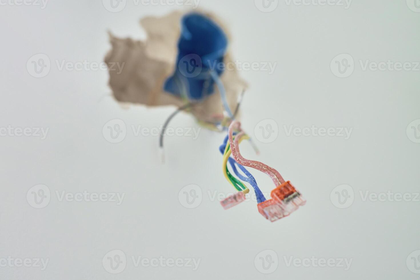 Colorful wires stick out of wall socket during renovation. Concept of electrical installation and construction photo