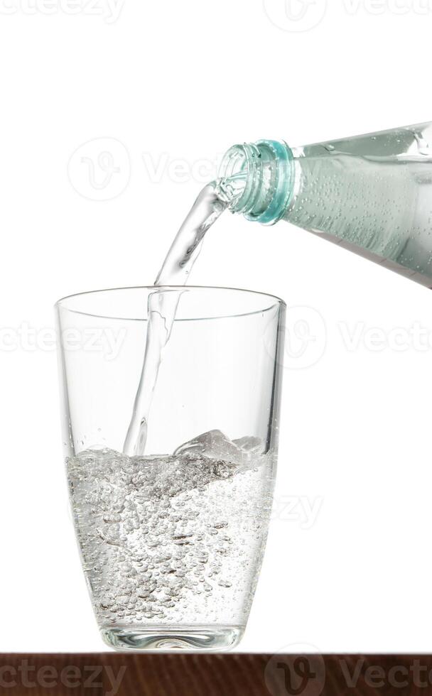 Pouring water into glass on table with isolated background photo