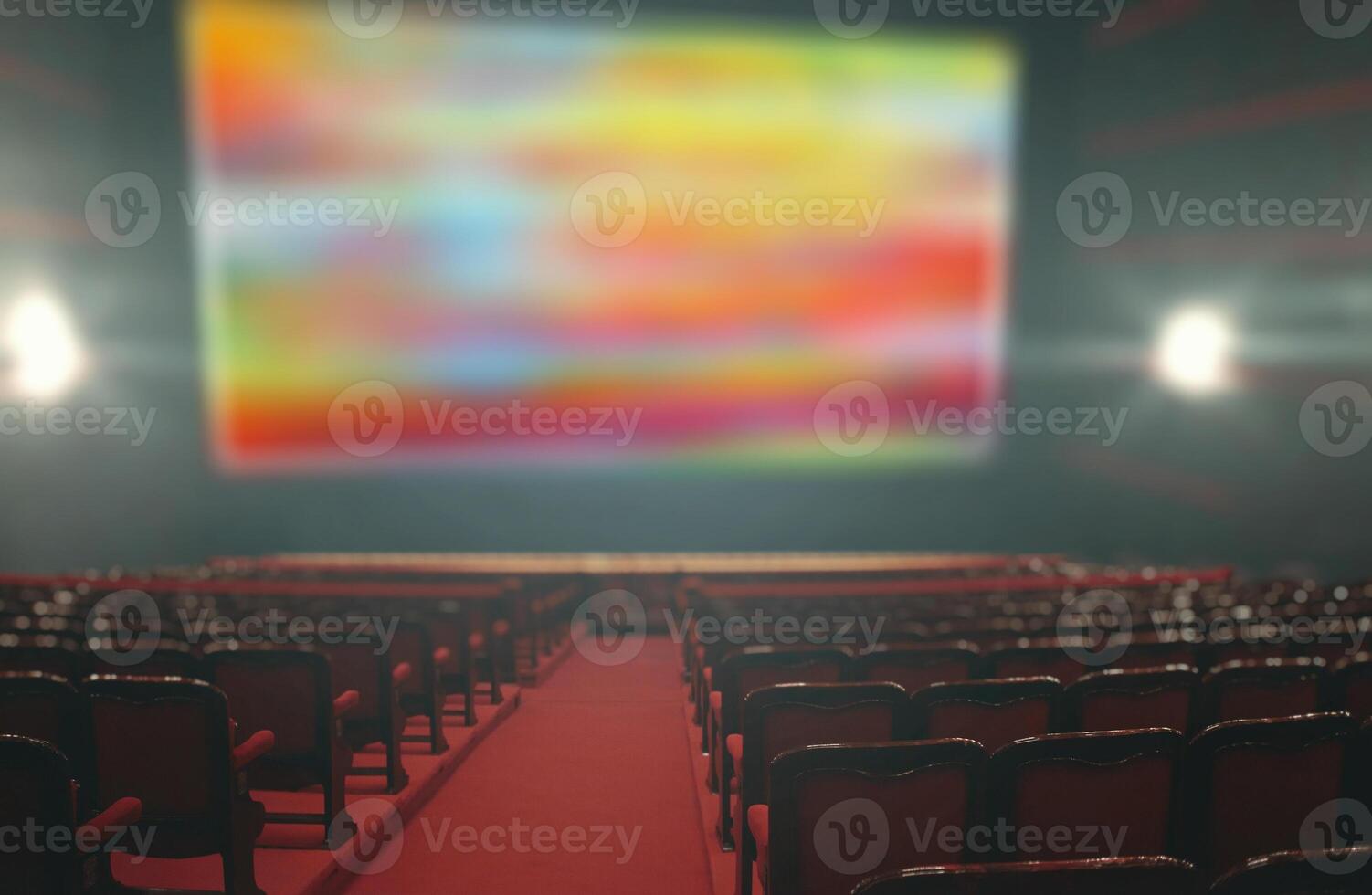 An empty theater with red seats and a large screen photo