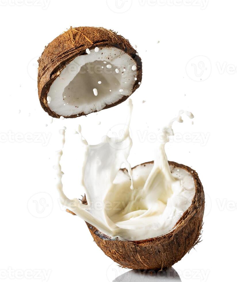 Broken coconut with a splash of milk on a white background photo
