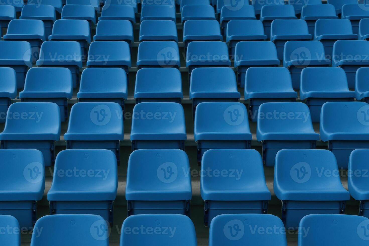 Symmetrical blue plastic stadium seats under soft diffused daylight atmosphere photo