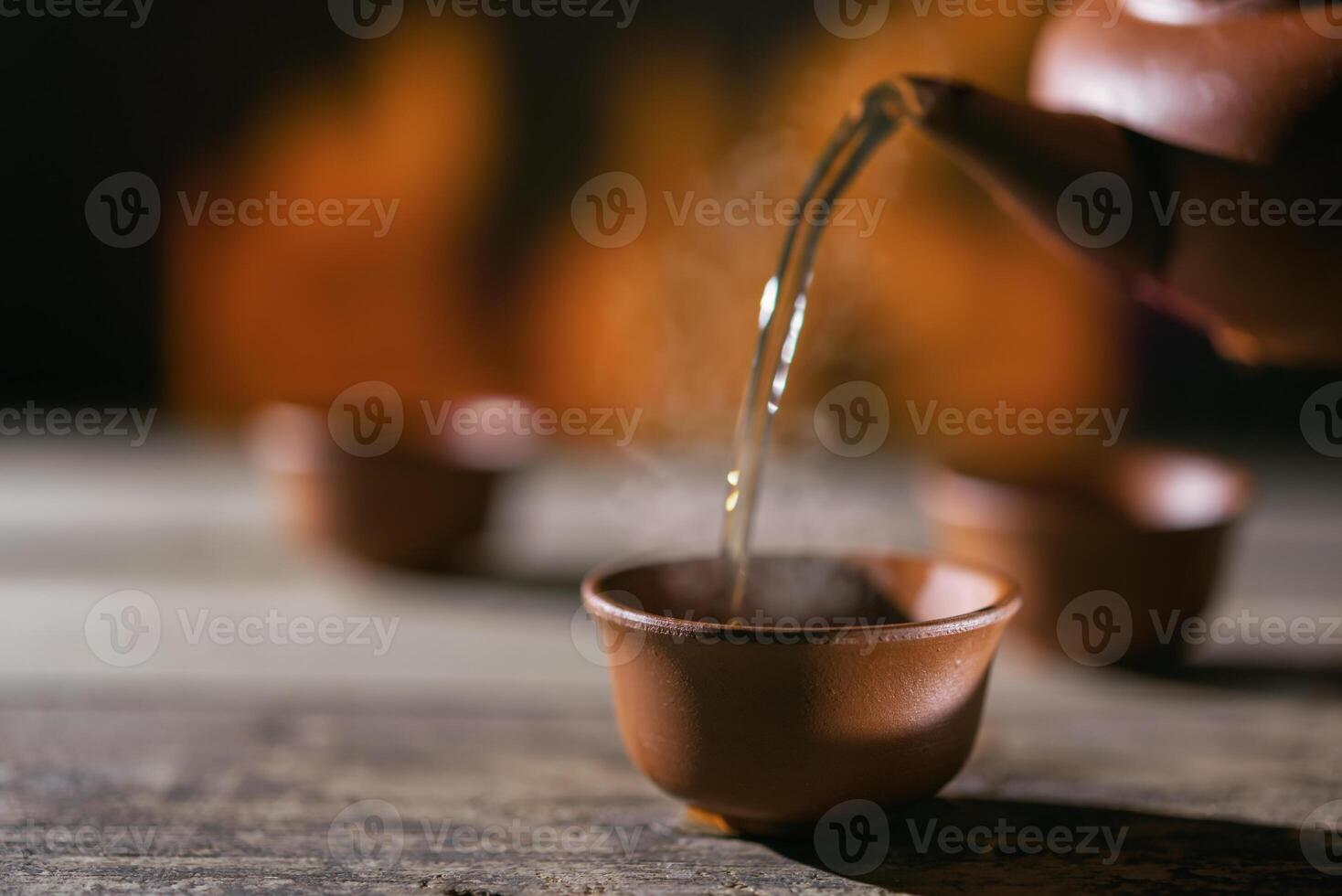 Pouring tea into a cup against the background of fire photo