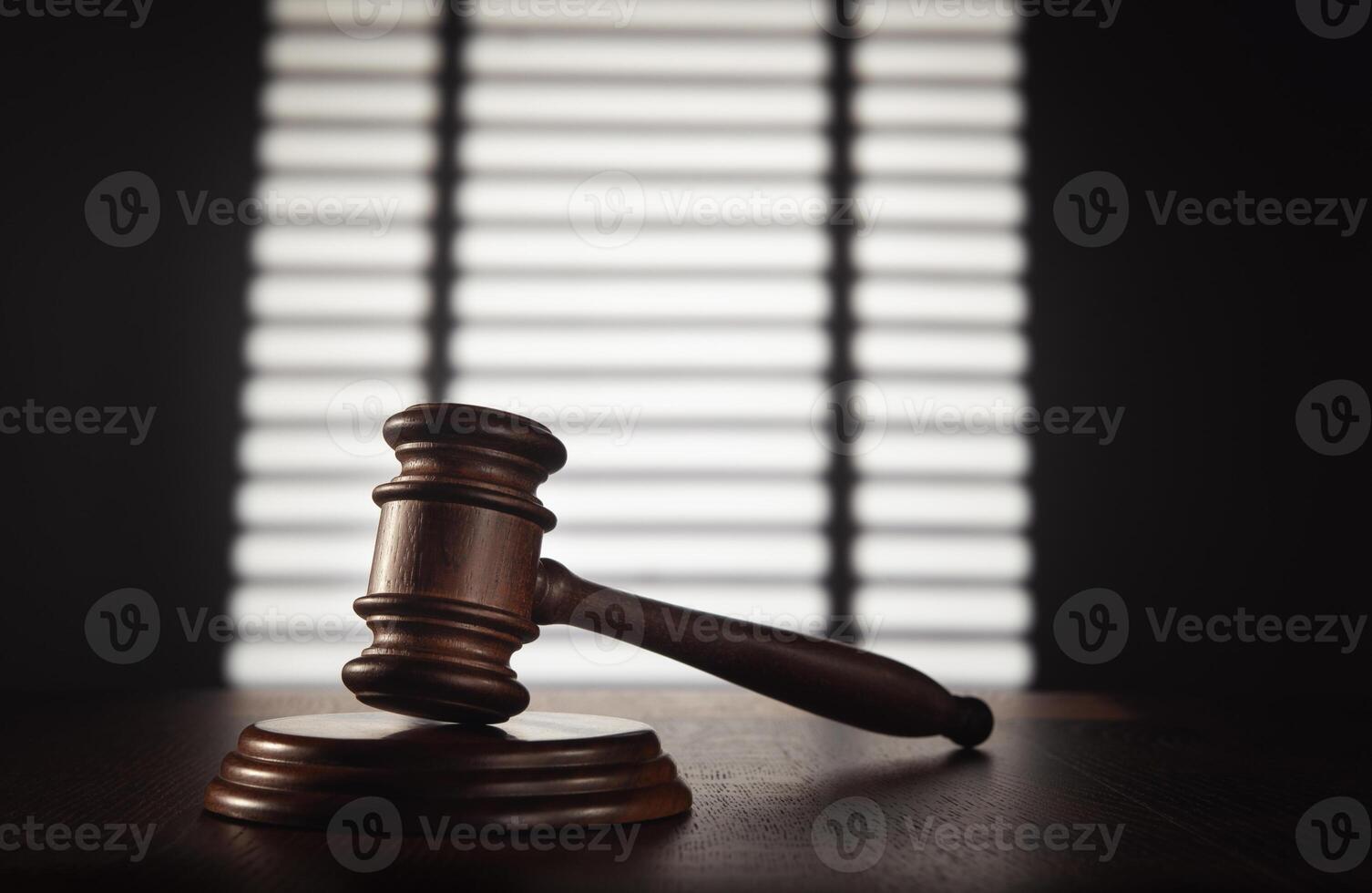 Judge's gavel on wooden table in front of blinds photo