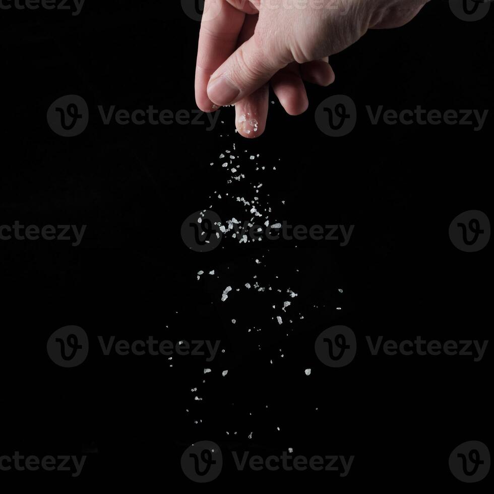 A person holding a salt shaker over a black background photo