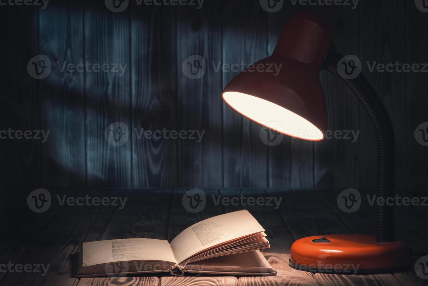 An open book and a lamp on a wooden table photo