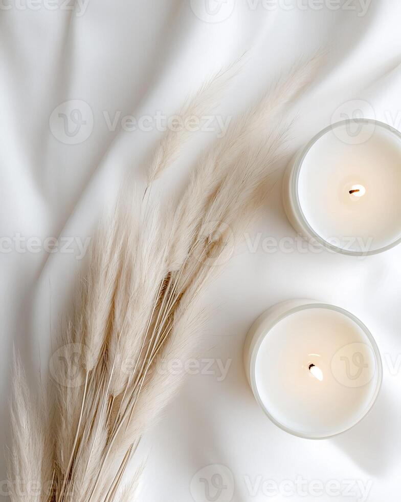 Two Lit Candles and Pampas Grass on White Fabric photo