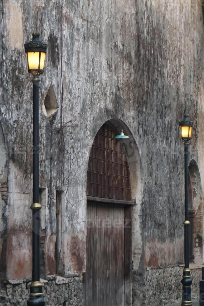 Bird flying arched doorway, ancient wall, lamps, Italy photo