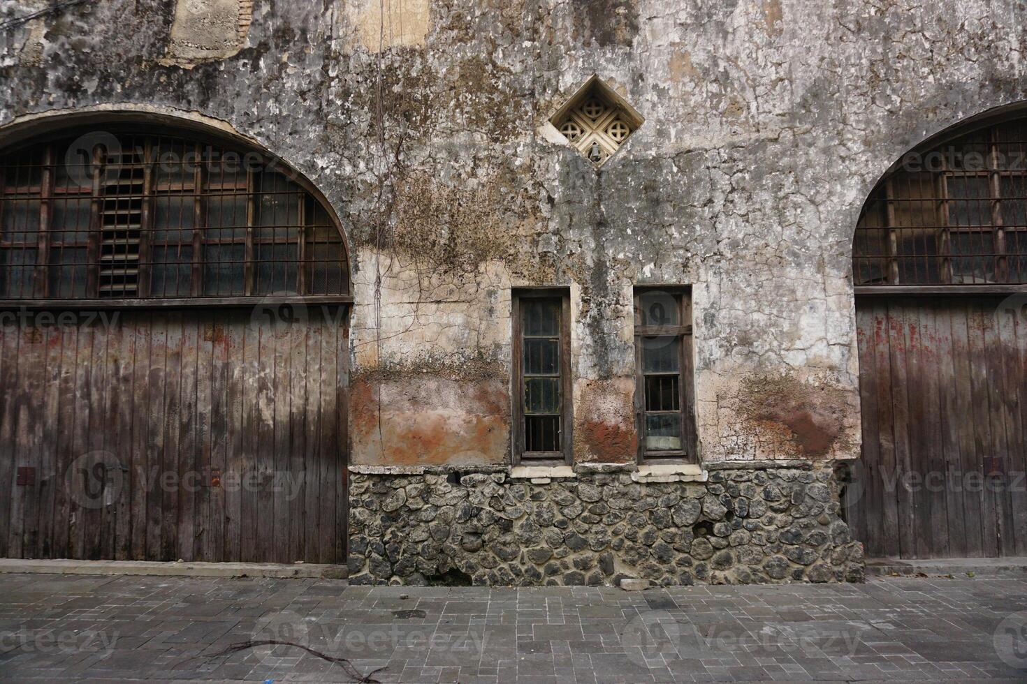 Old weathered building facade, wood doors, stone base, urban setting, historical architecture photo