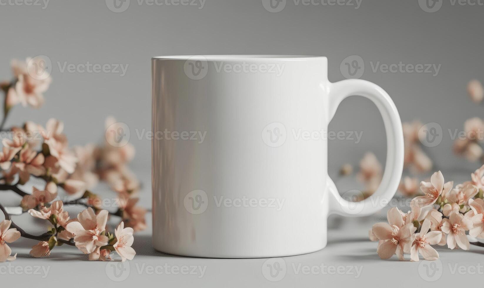 A white coffee mug sits on a table with pink flowers in the background photo