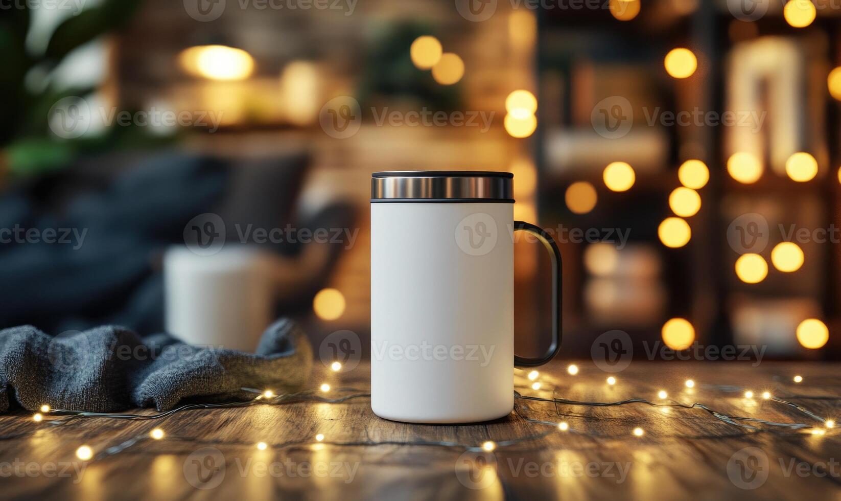 A white coffee cup sits on a wooden table with a blanket draped over it photo
