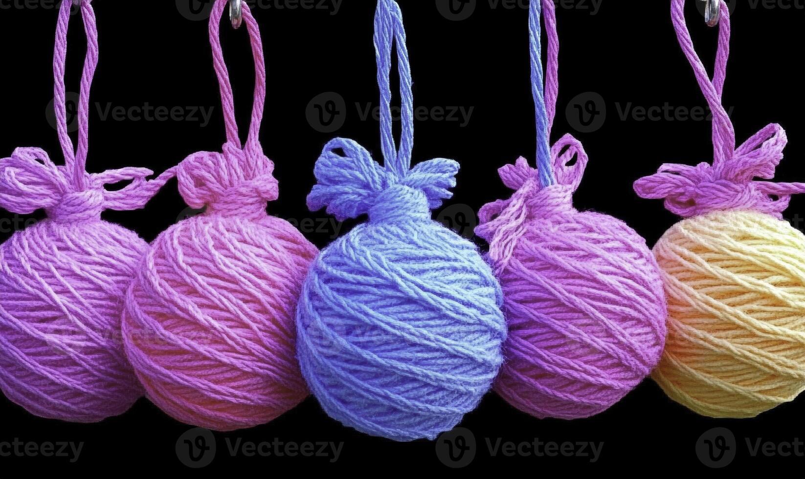 Four colorful yarn balls hanging from strings photo