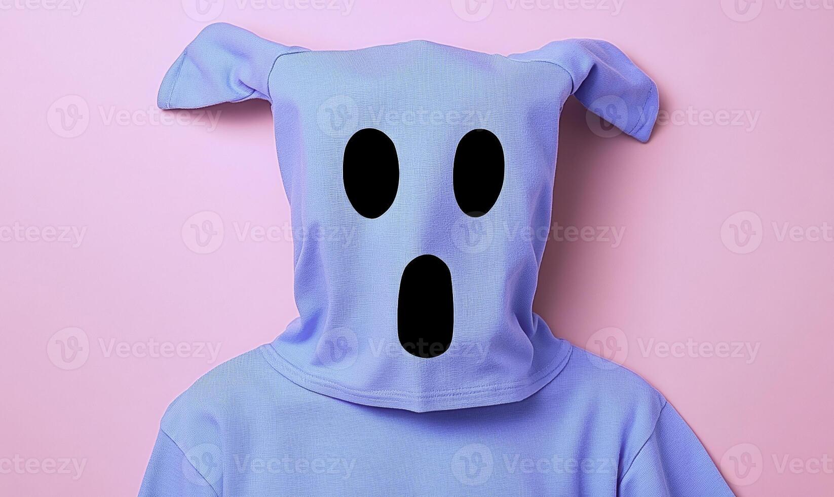 Surreal blue hoodie with ghostly face on soft pink background capturing playful and whimsical fashion expression for modern youth culture photo