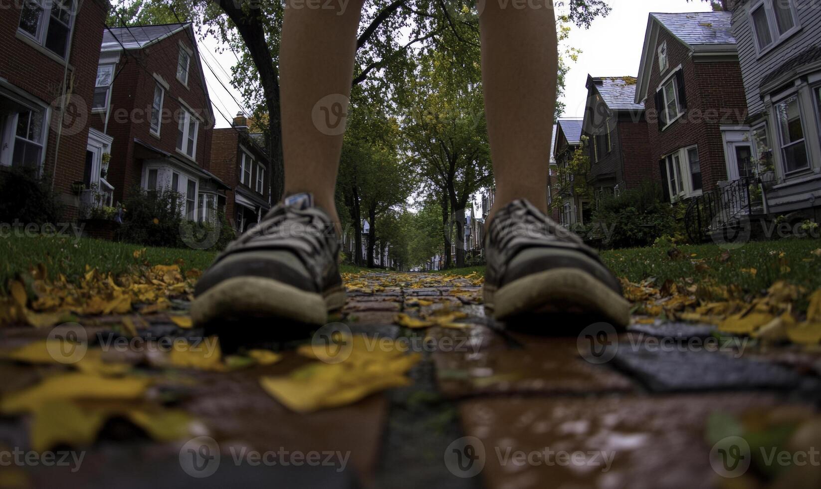 A person wearing sneakers walking down a sidewalk photo