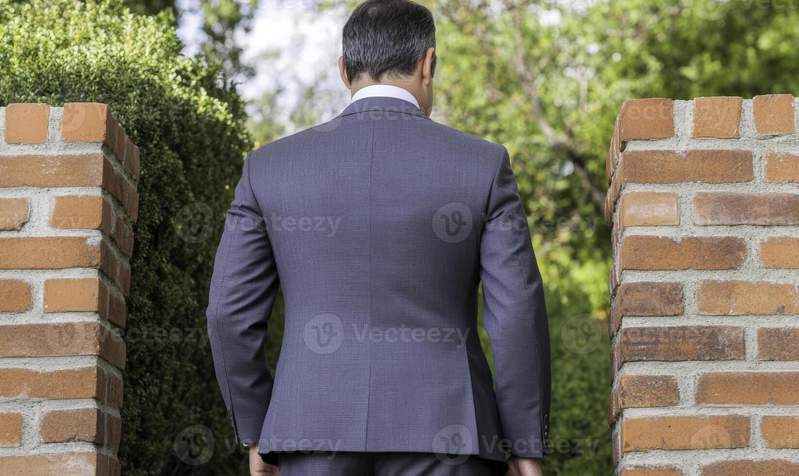 A man in a suit standing in front of a brick wall photo