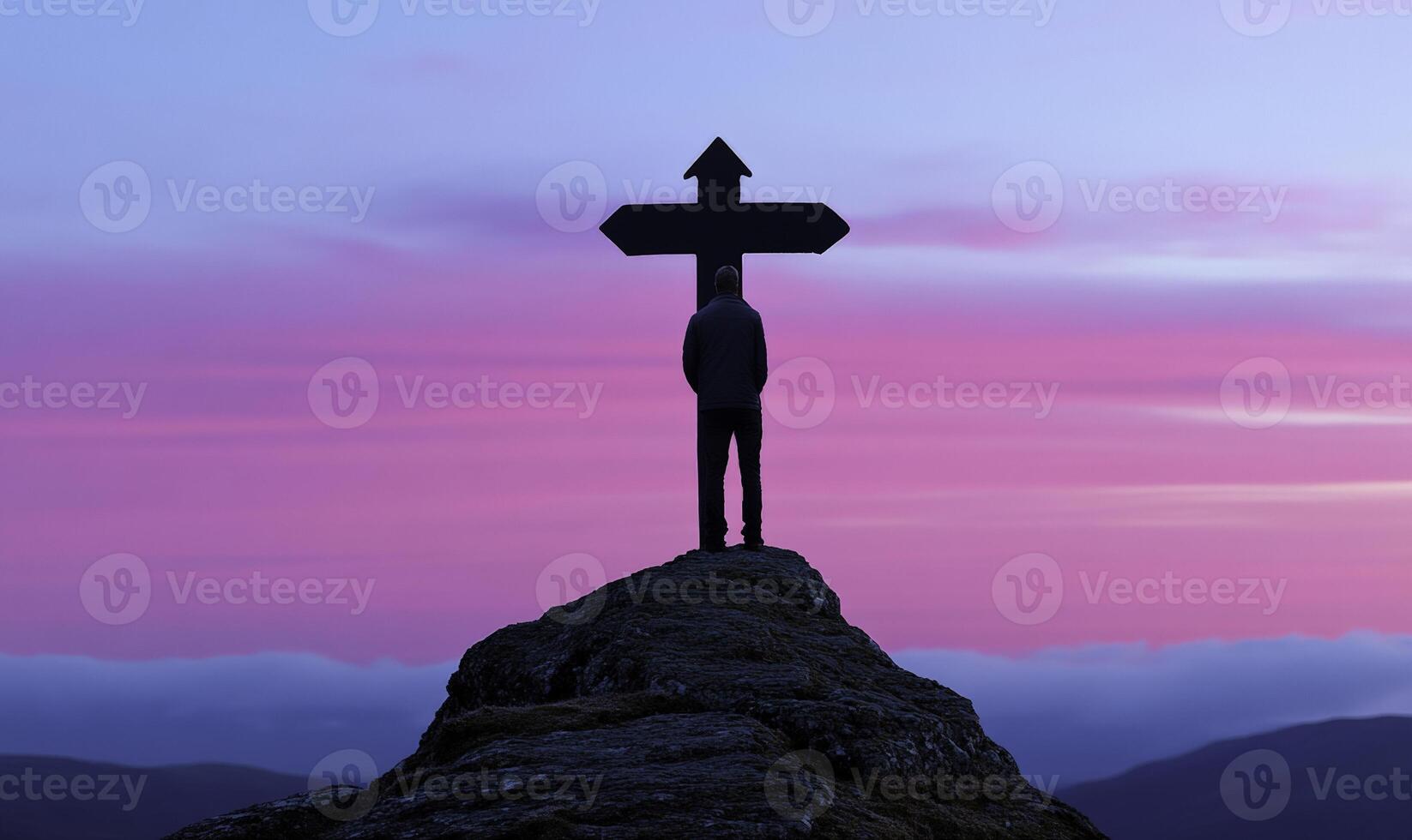 Silhouette of a Person Standing on a Rock with a Cross Against a Vibrant Sky at Sunset, Symbolizing Choices and Directions in Life photo