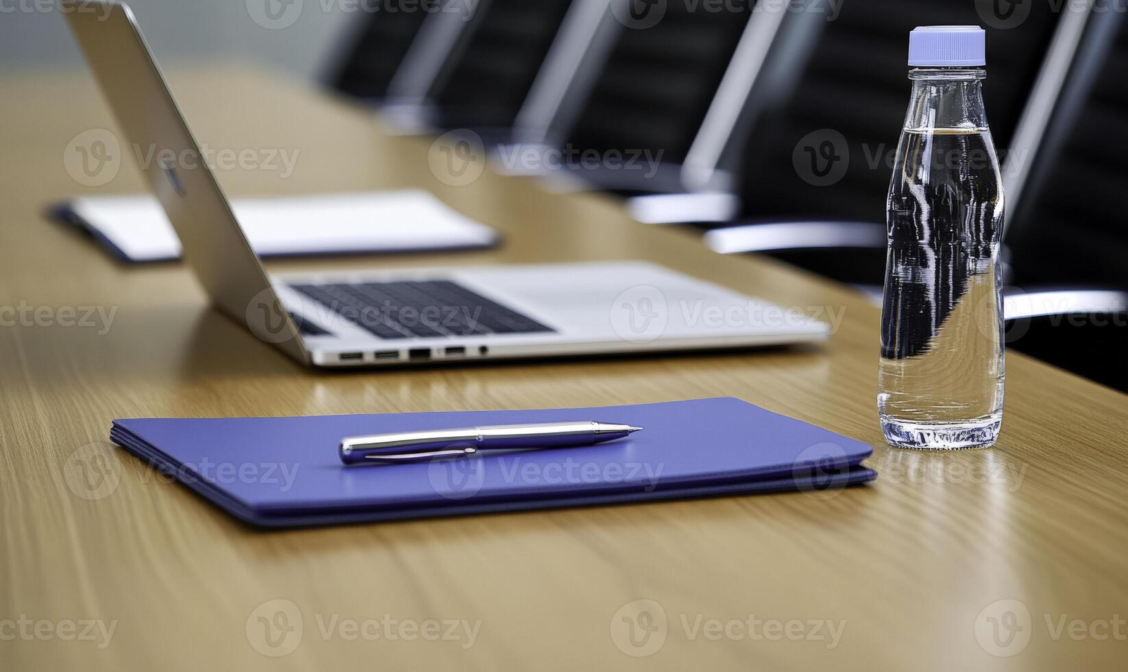 Modern office workspace with laptop, blue folder, pen, and water bottle on wooden table, showcasing minimalistic design for business and meetings photo