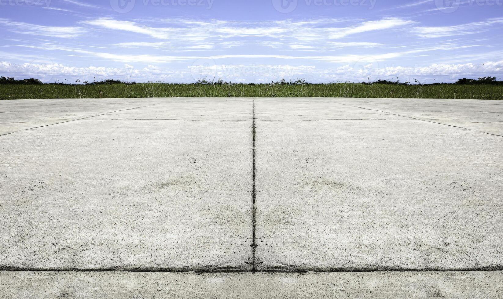 Vast Expansive Concrete Ground with Clear Blue Sky and Lush Green Grass, Ideal for Backgrounds and Texture in Scenic Photographs and Designs photo