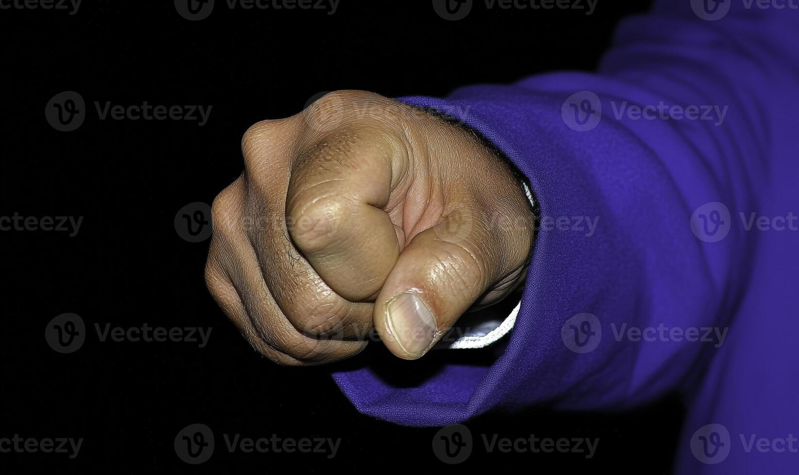 Close-up of a clenched fist symbolizing determination and strength in a dark environment showcasing human emotion and power dynamics in society photo