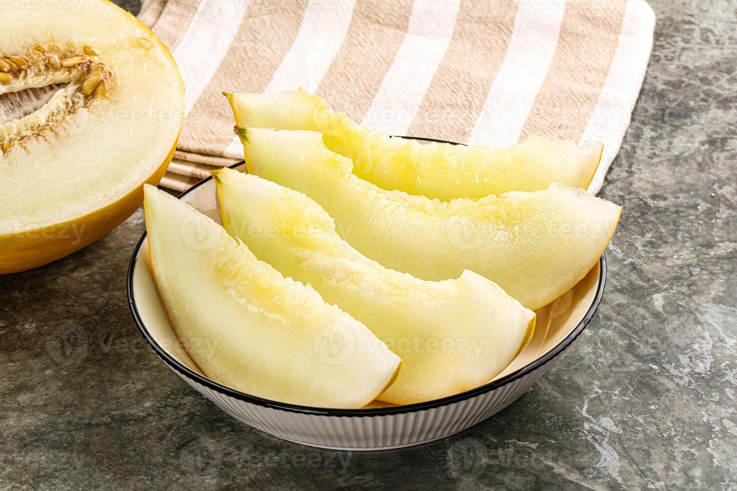 A bowl of sliced melon sitting on a table photo