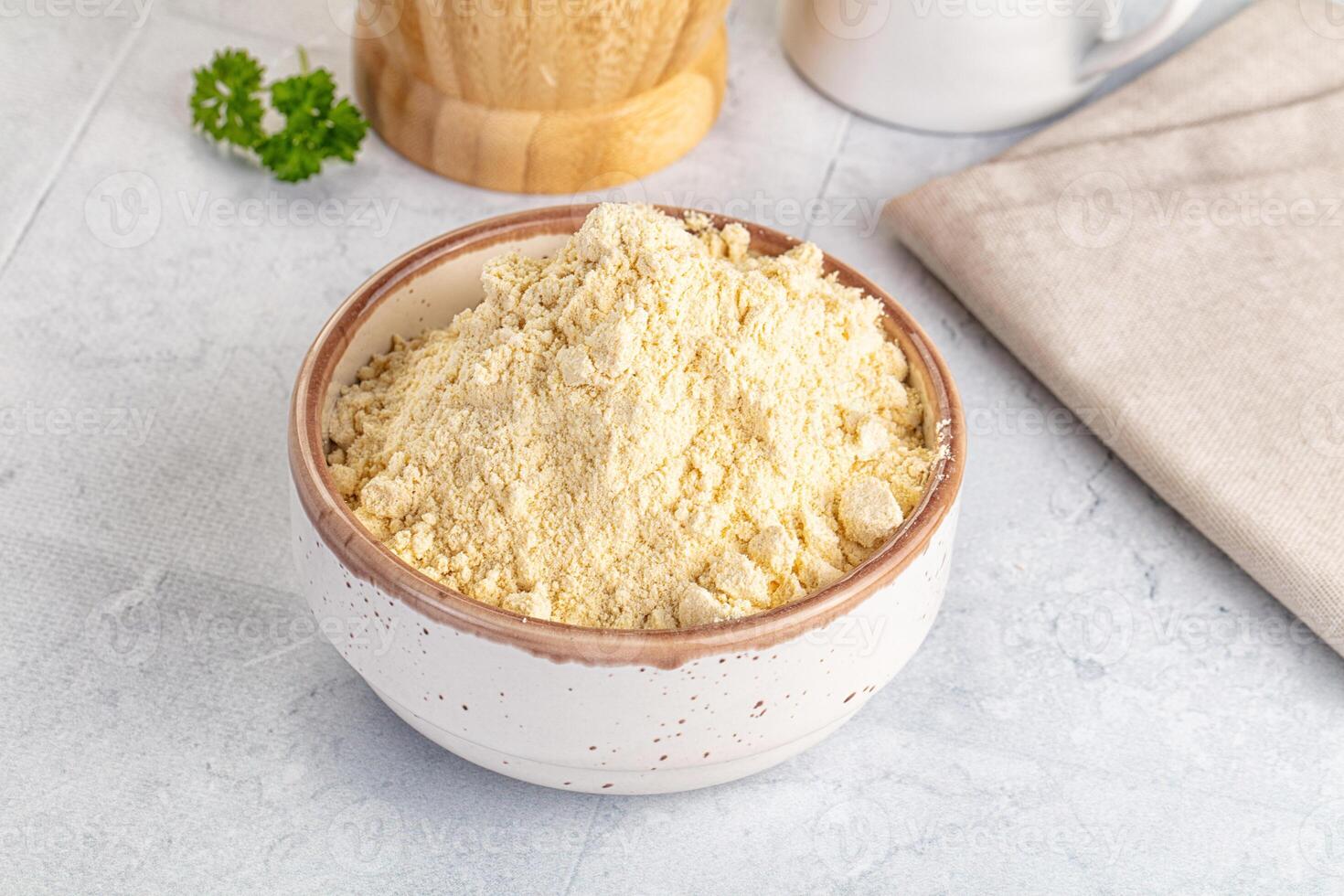 A bowl of flour and a wooden spoon next to a cup of milk photo