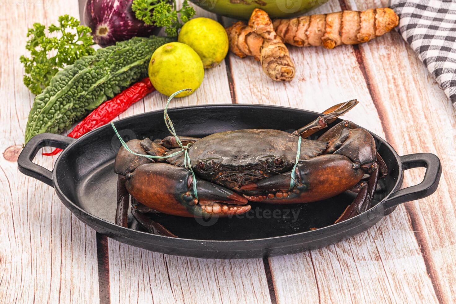 A crab is sitting in a pan with vegetables photo