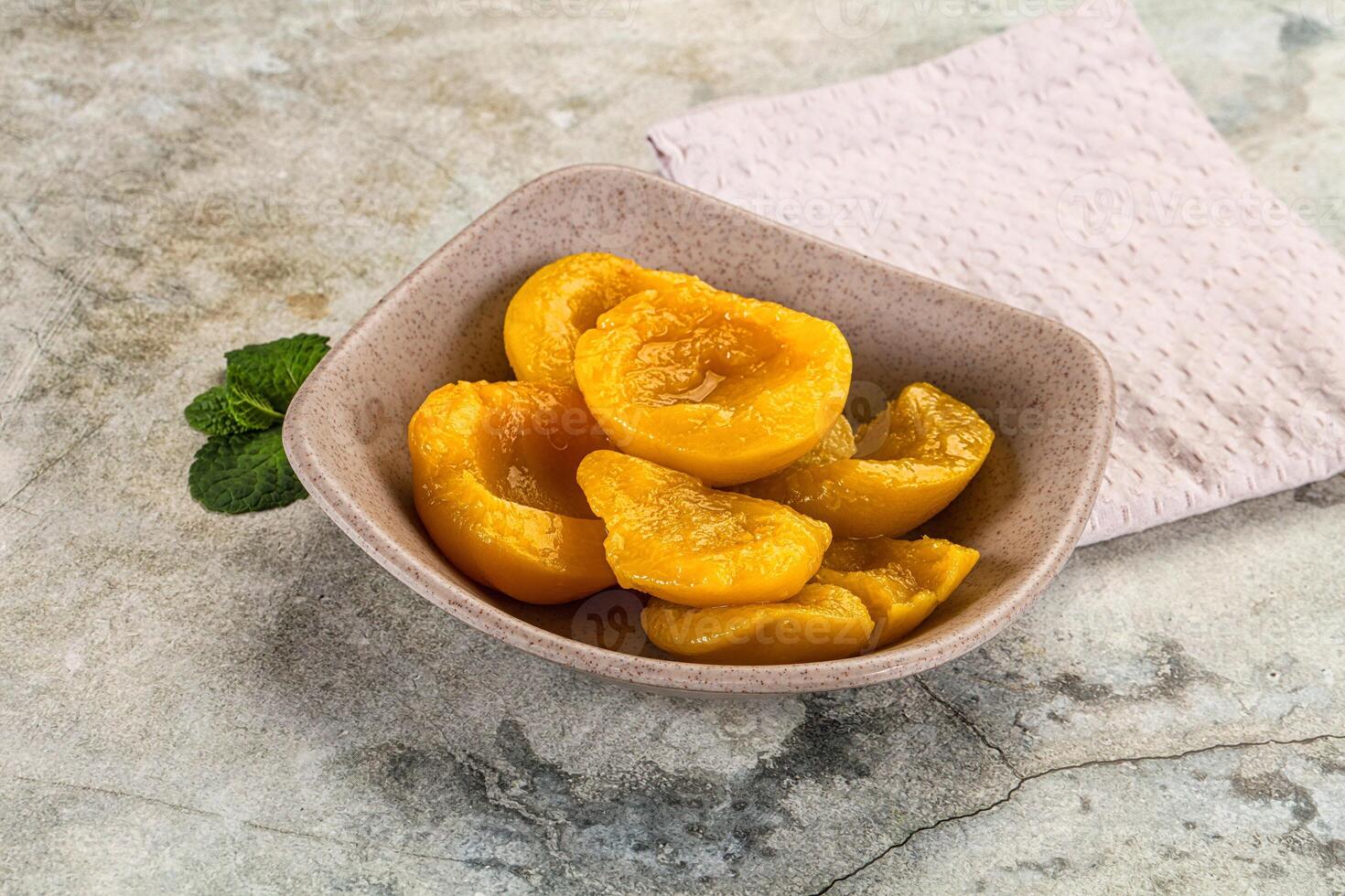 A bowl of peeled apricots on a table photo