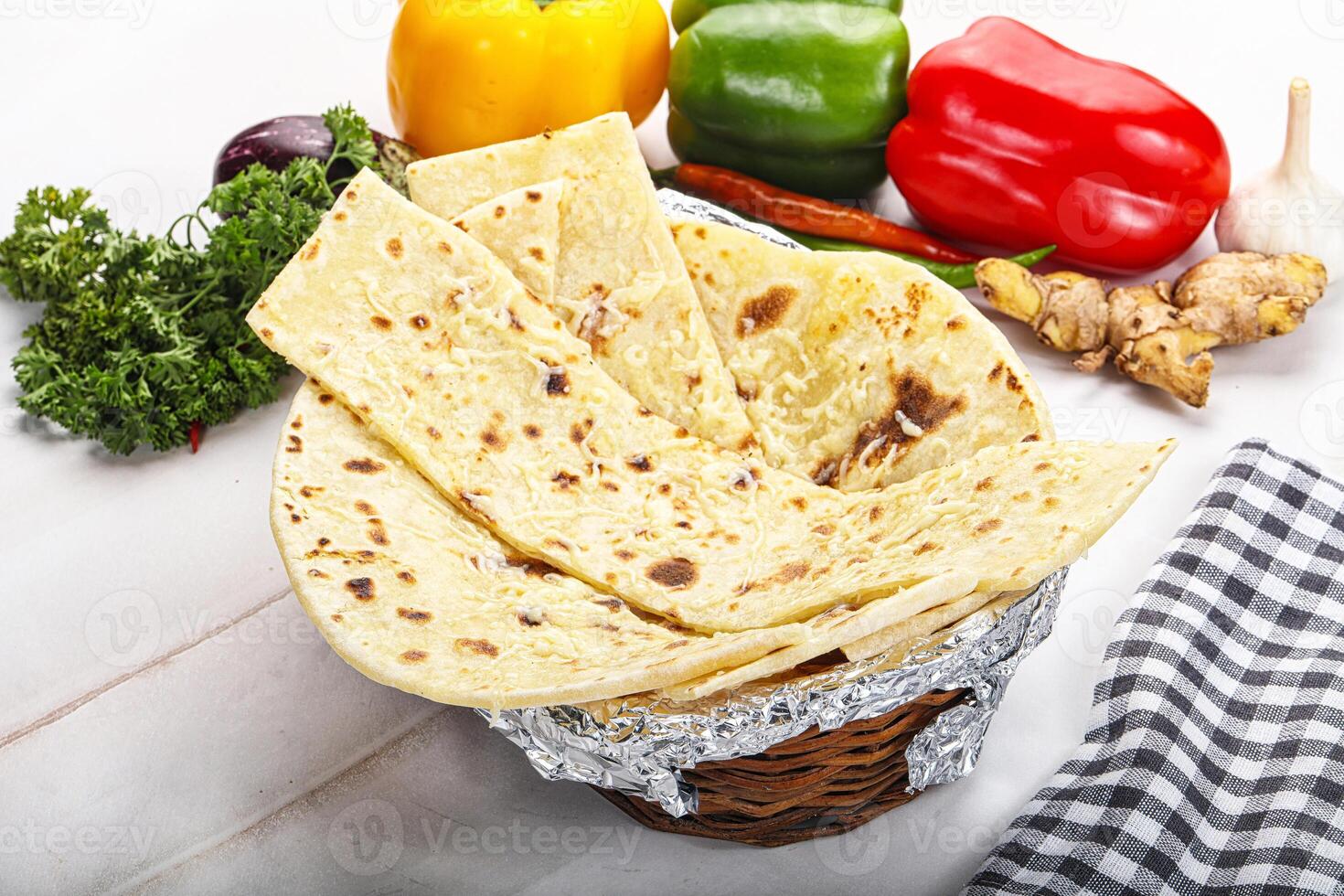 A basket of tortillas on a table with vegetables photo