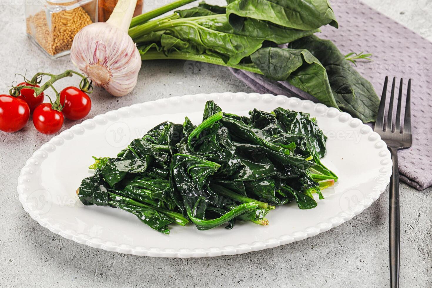 Spinach with garlic and tomatoes on a white plate photo