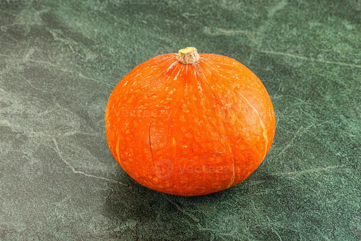 A small orange pumpkin on a green surface photo