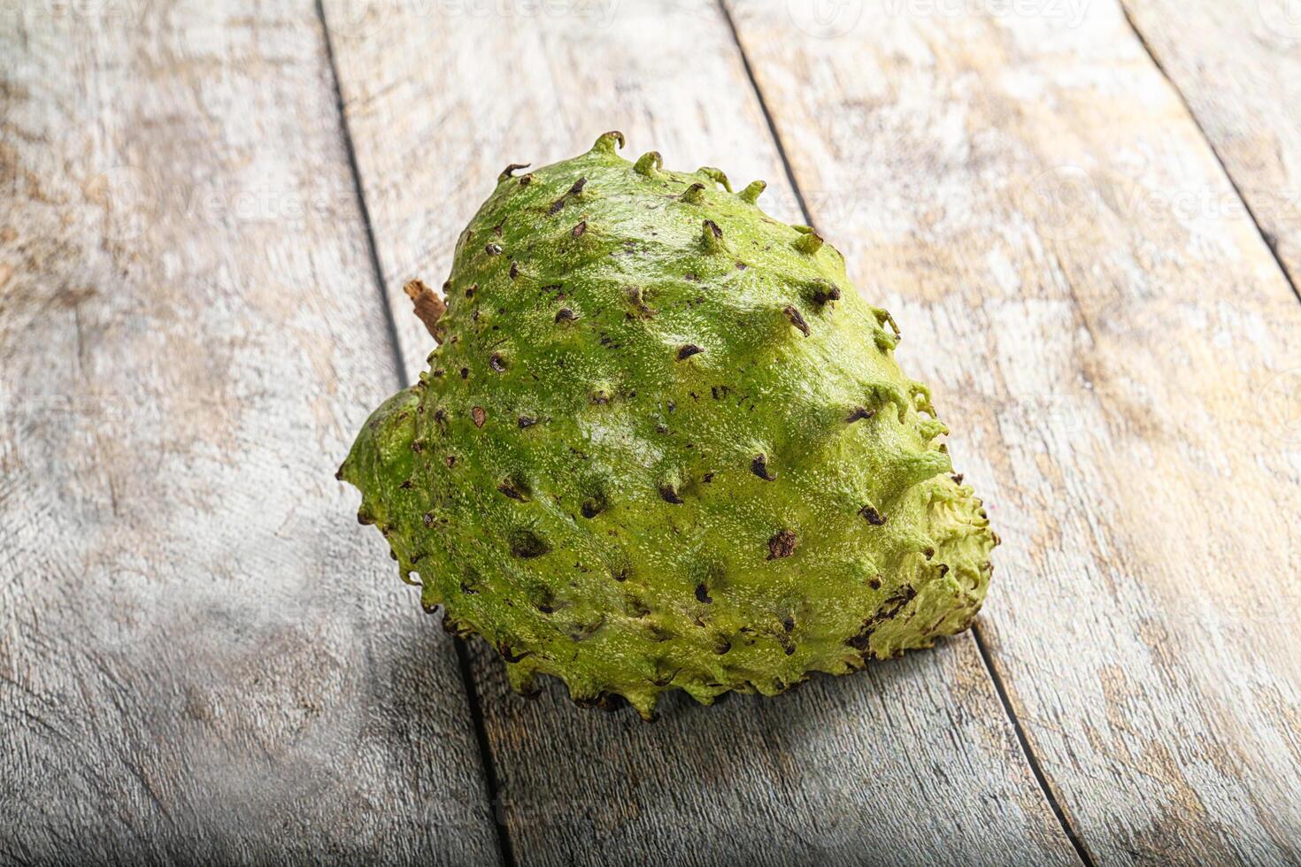 A single green fruit on a wooden surface photo