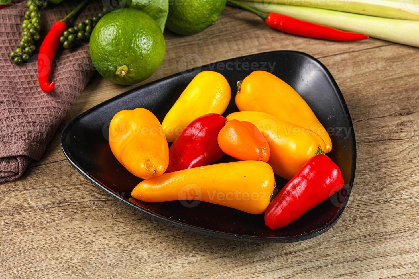 A bowl of peppers and limes on a table photo