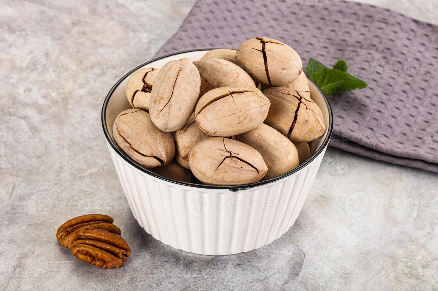 Pecan nuts in a white cup on a gray background photo