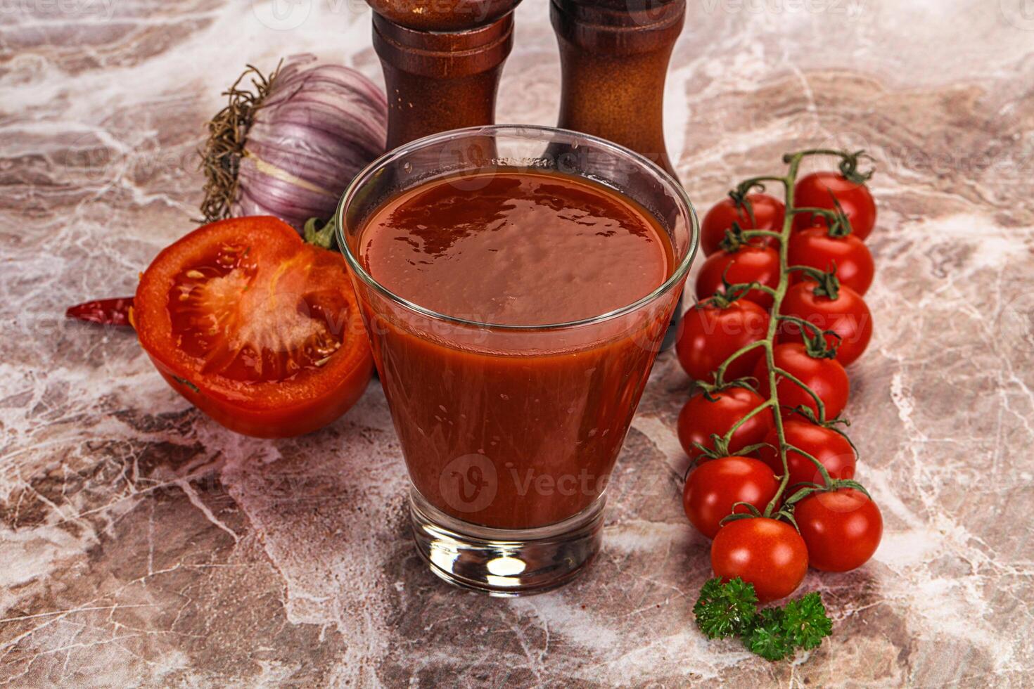 A glass of tomato juice next to a bunch of tomatoes photo