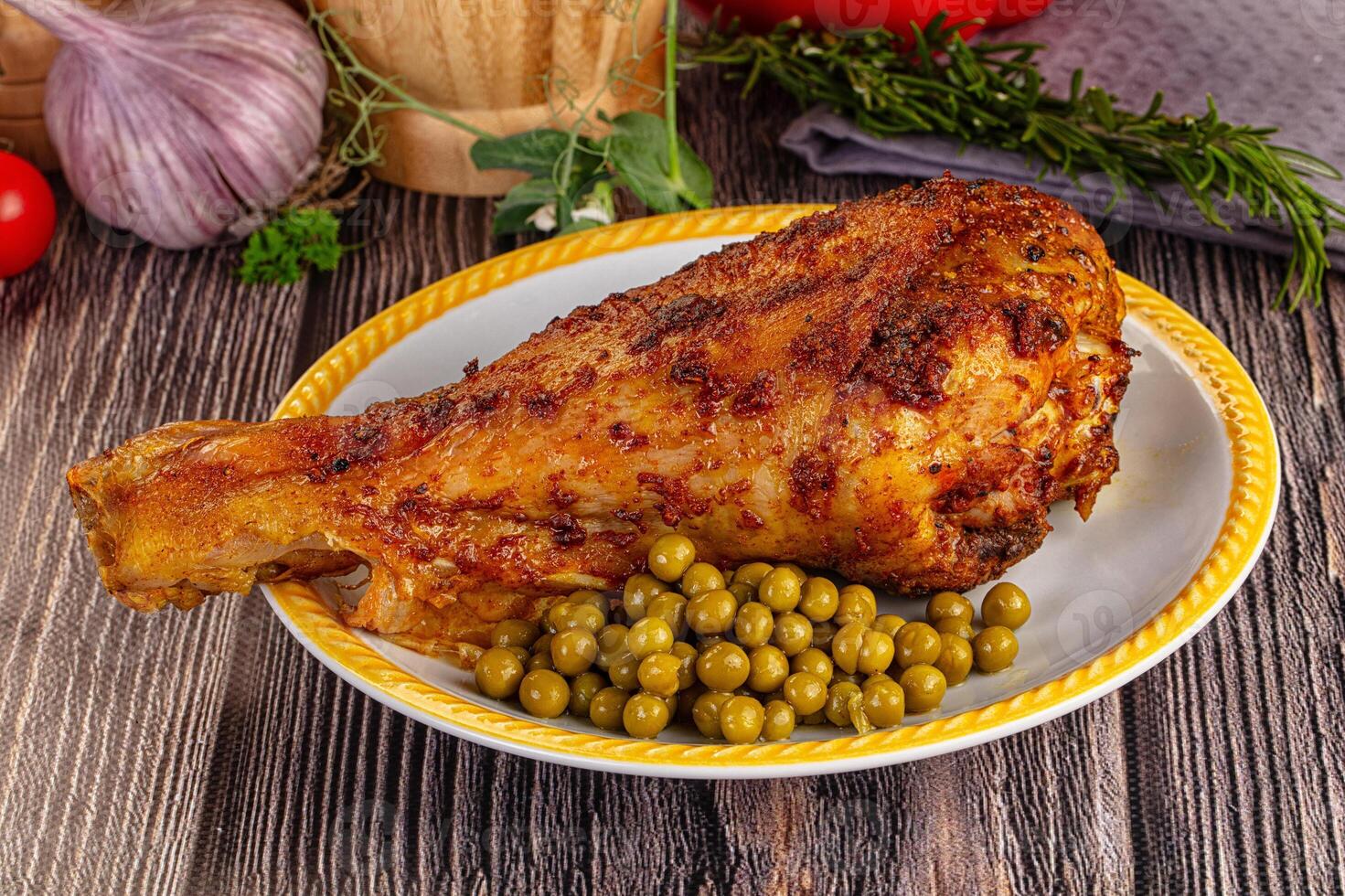 A plate with a chicken leg, peas and tomatoes photo