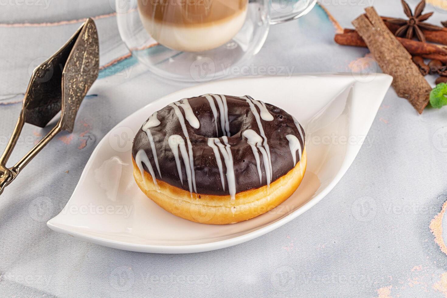 A donut on a plate with a cup of coffee and spices photo