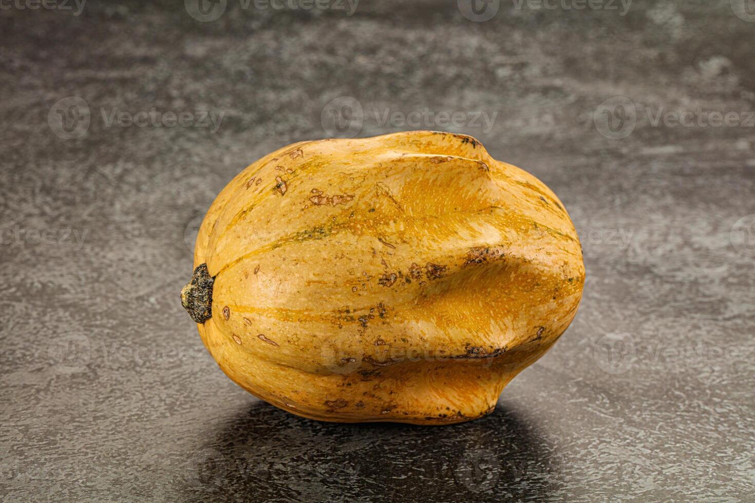 A yellow squash on a black surface photo