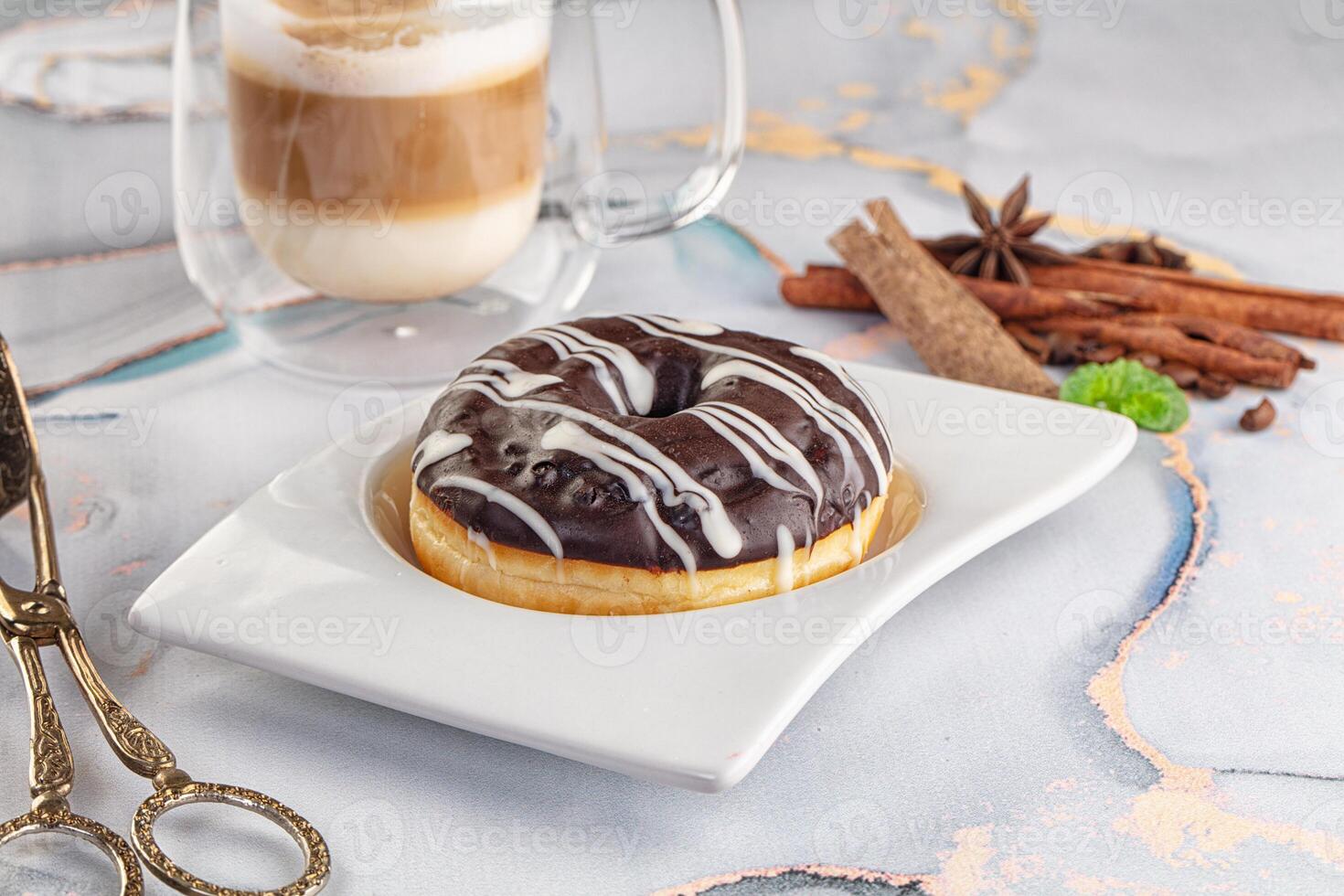 A donut on a plate next to a cup of coffee photo