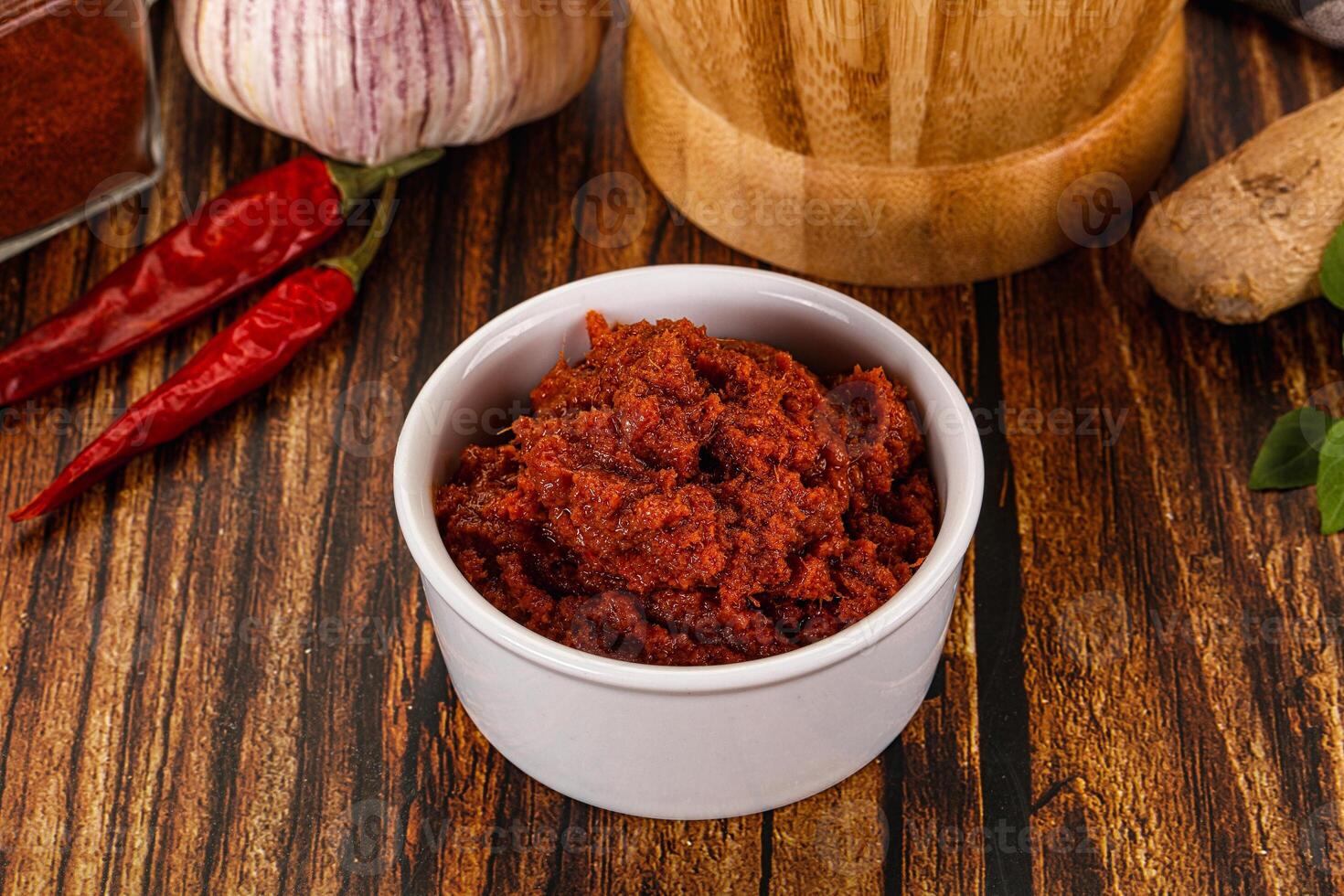 A bowl of chili powder next to a knife and a garlic clove photo