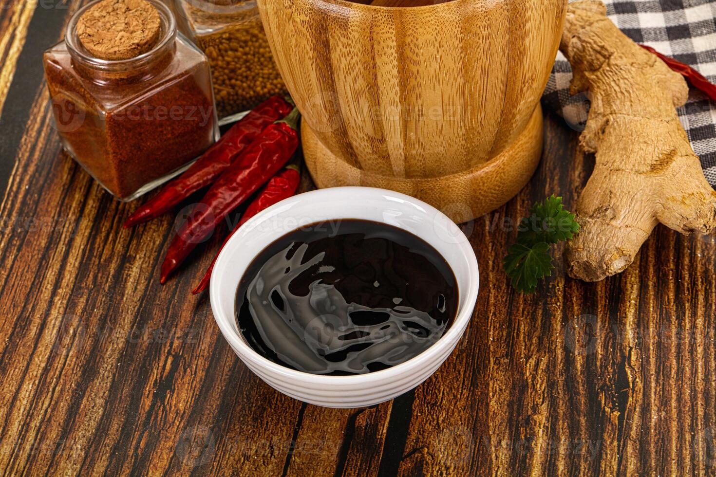 A wooden table with a bowl of black liquid and spices photo